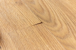 A photo of the corner of a creamy brown laminate plank lifting slightly 